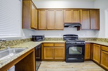 A kitchen with wooden cabinets and granite countertops